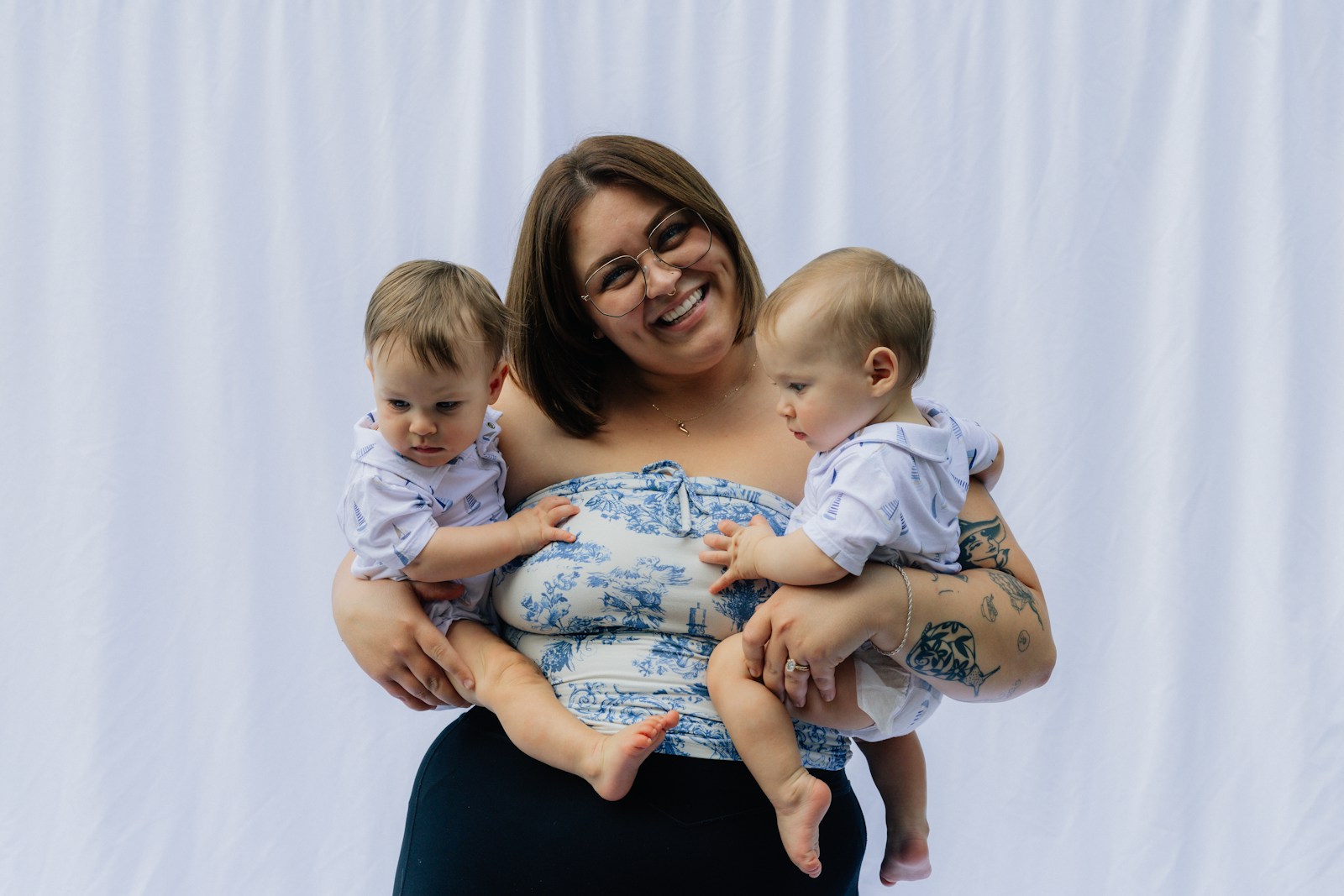 Woman holding two babies in front of white backdrop